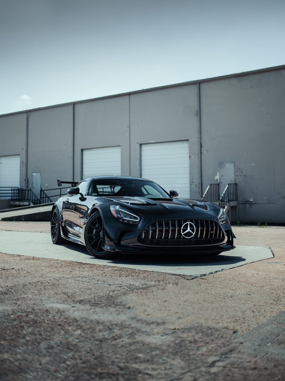 Black Mercedes-AMG GT parked in front of a warehouse